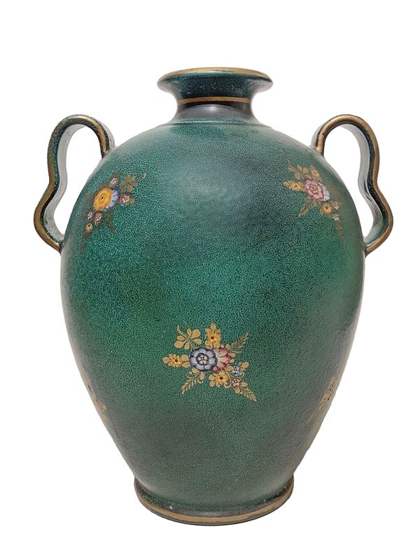 Majolica vase on green backfloor, with floral decorations.