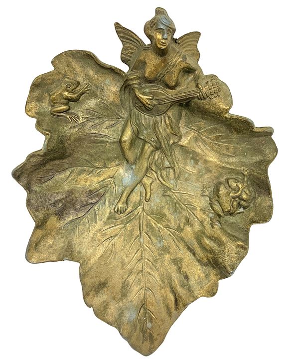 Gold zamak coin tray depicting a leaf with a woman playing