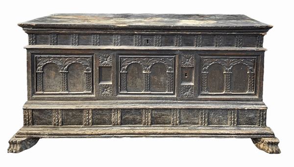 Cassapanca in legno di noce intagliata sul fronte con colonne e archi.