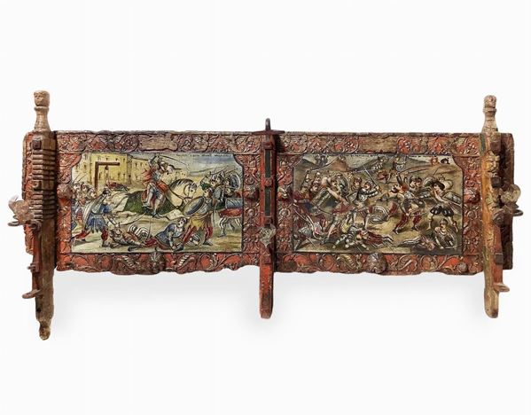 Sicilian cart "sponda" painted wooden two scenes, the late nineteenth century, Sicily. H 48x125 cm. Roger Milo free from the gallows, fighting Acolaccio in the valley, and death of Astolfo. Sculptures grotesque and floral motifs carved on the frame and iron sculptures depicting Paladins, Dragons players and angels H Cm 60 x122x13.