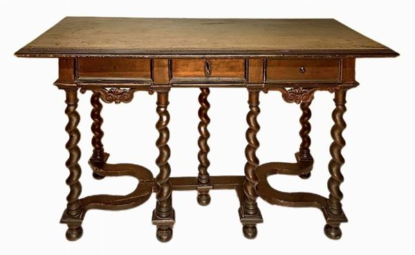 Tavolo scrittoio in legno massello di noce da muro, Luigi XIII, secolo XVII. Piano bordato a becco di civetta, tre cassetti al sottopiano n. 7 strutture a torciglione terminanti con basi a cipolla schiacciata. H cm 78x142x73