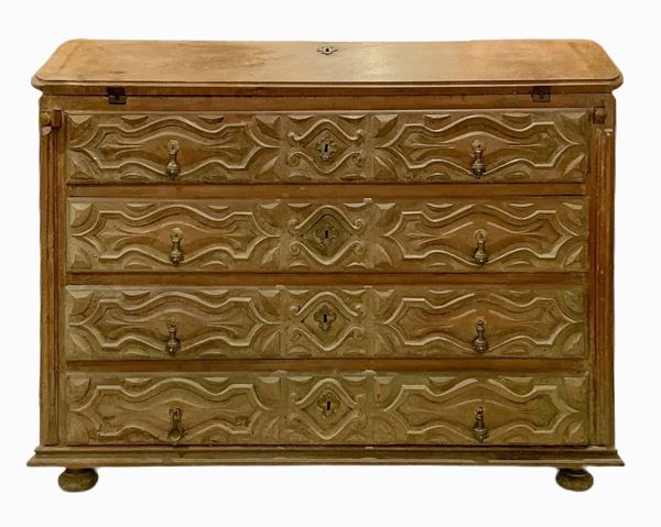 Ribalta in legno di rovere, Francia , XVIII secolo. Sul fronte quattro cassetti intagliati in tre sezioni con forma oblunga recante pendente a tiretto e al centro bocchetta in bronzo. Sui fianchi intagli divisi in due grandi sezioni. Ferramenta originali, piedi rotondi schiacciati. All'interno piano della ribalta sostituito. H cm 108x132x55