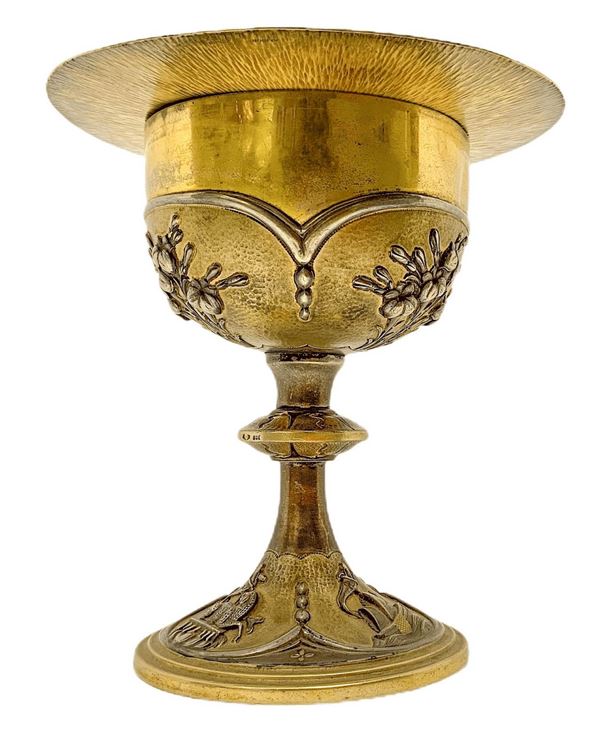 Calice con patena in argento vermeil decorato a sbalzo con motivi floreali, primi XX secoli. Sulla base simboli religiosi. H cm 15 . Gr 490 . Con custodia originale.
