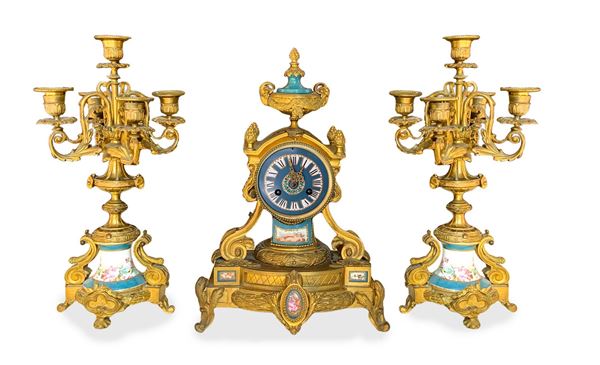 Trittico composto da orologio e coppia di candelieri a 5 luci con inserti in porcellana nei colori del Sevres, Napoleone III, metà XIX secolo .Orologio H 48. Base cm 32x19. Candelieri H cm 44
