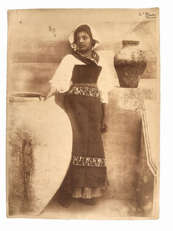 Wilhelm von Gloeden (1856-1931), vintage photo print on salted paper depicting "Young Siciliana in traditional clothes", c 1911. Signed at the top right. Numbered "37" and hallmarked on the back. Foxing stains on the reverse.

"Wilhelm Von Gloeden was a German-born photographer who spent most of his life in Sicily, specifically in Taormina, a city that he chose as a second home. It was the youth health issues to take in the peninsula. Specifically, the choice of Taormina is linked dreamy ideal