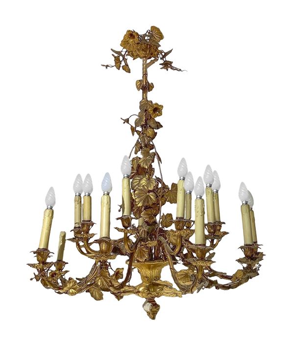 Grande lampadario in bronzo e ottone dorato al mercurio, a 18 luci, con decori a ramage di foglie.