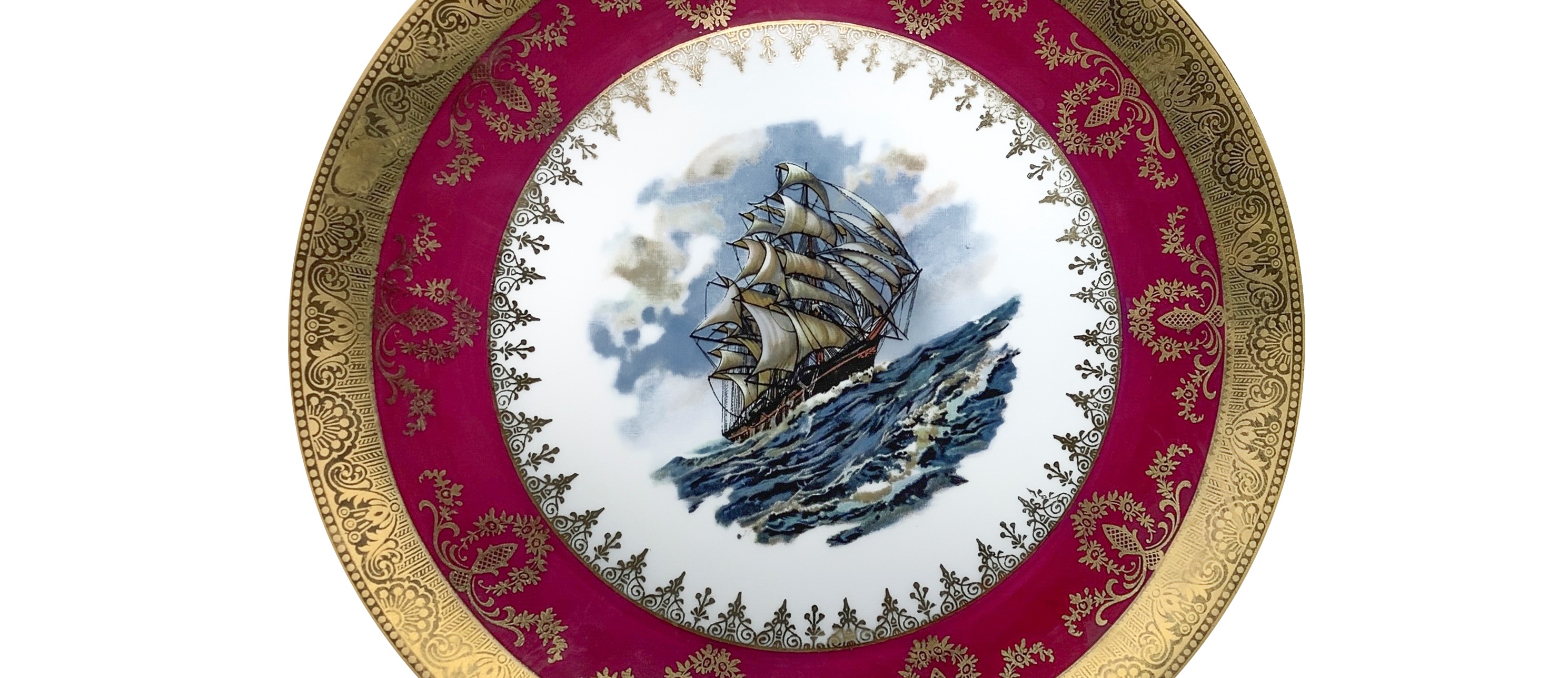 Coppia di piatti in porcellana bordeaux e oro con un galeone al centro