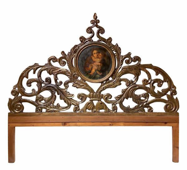 Testata da letto in legno dorato scolpita a larghe foglie d'acanto con tondo centrale portante sacra  [..]