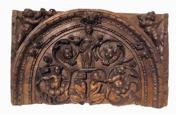 Frammento di fregio in legno di noce scolpito raffigurante Santa Barbara con puttini e satiri, XVII/XVIII secolo. Cm 42x67