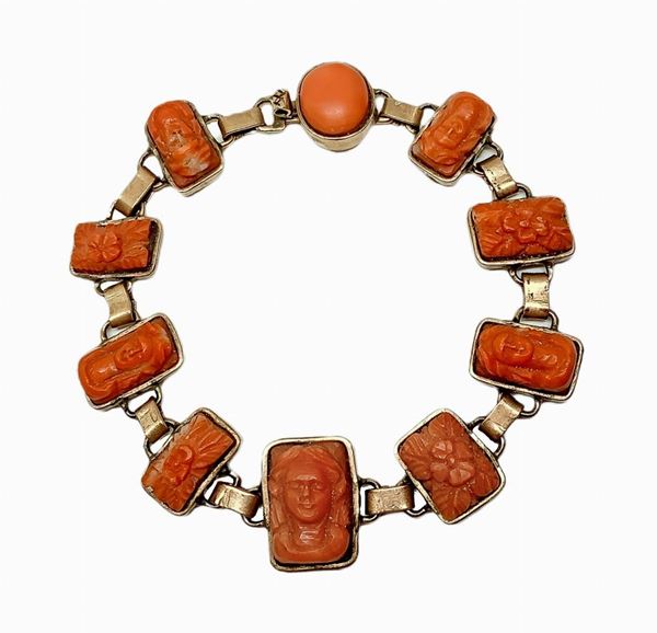 Bracelet in coral, with 11 miniatures depicting faces and floral decorations. Overall length of 19.5 cm