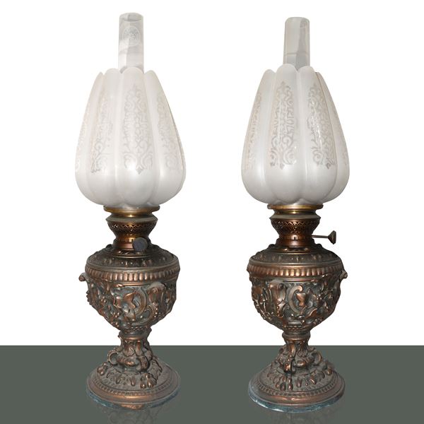 Pair of oil lamps with brass base embossed in relief with floral motifs