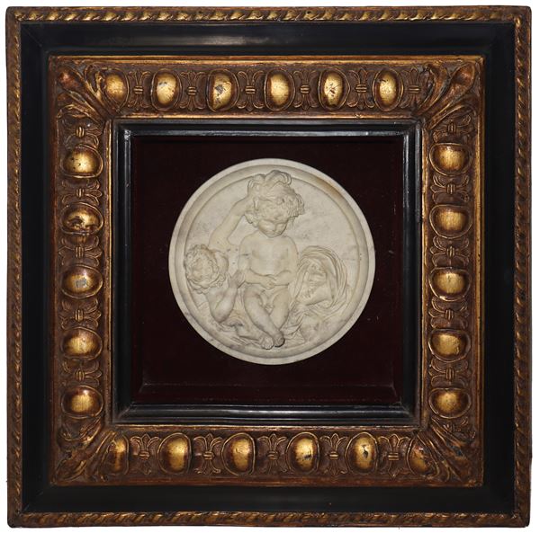 Oval bas-relief depicting cherub games in a golden frame