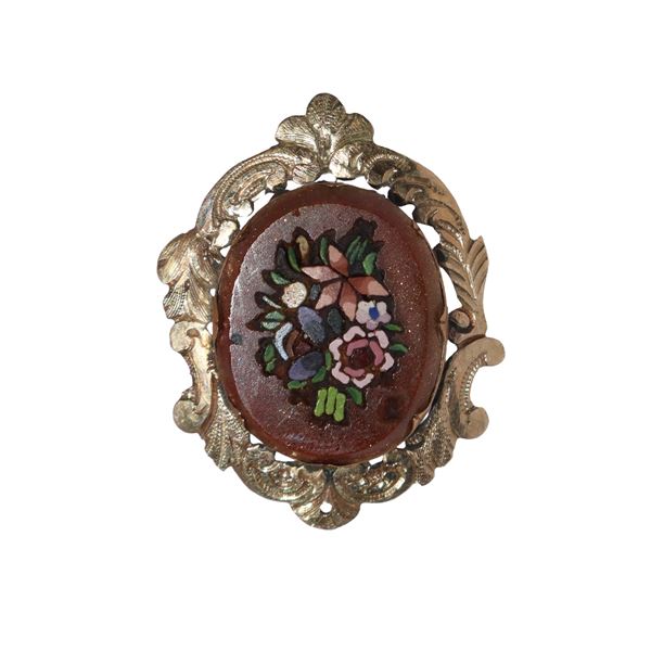 Low-title gold brooch with commissions of semi-precious stones in mosaic with floral motifs.