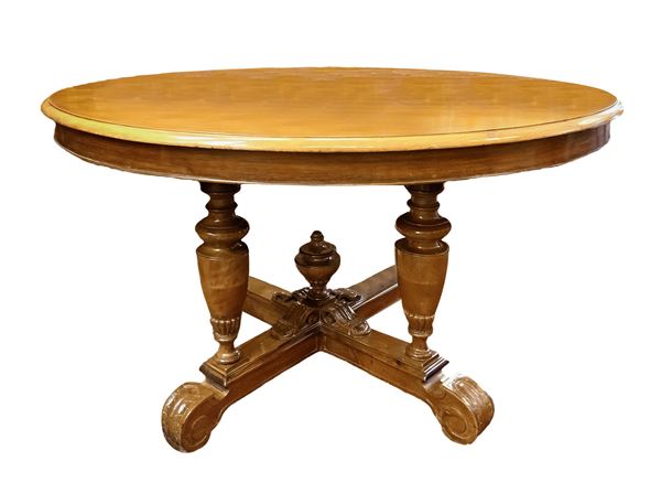 Tavolo da pranzo in legno di noce allungabile con piano ovale retto da quattro balaustre con piede a quattro razze, pigna al centro sulla crociera. 