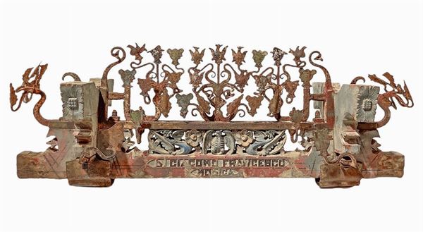 Frammento di carretto, fascia di fuso. In legno policromo scolpito a putti, mascheroni e ferro battuto alla forgia in stile barocco con teste di paladini con elmo e aquile, Autore Di Giacomo Francesco, Modica, Catania, Sicilia fine XIX secolo, inizi XX secolo. H Cm 40x100