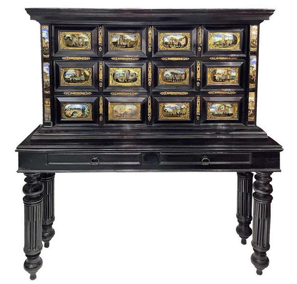 Monetiere in legno nero ebanizzato a due corpi. XVIII secolo. Avente come base tavolo in legno ebanizzato, 12 formelle ai cassetti di pittura su ... 