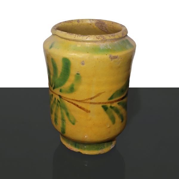 Cilindro in maiolica di Caltagirone, invetriato giallo, con decorazioni di foglie. 
