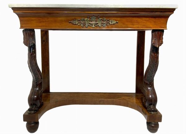 Console in legno di noce, inizi secolo XIX. Con piedi a delfino, marmo al piano e applicazione centrale in ottone. H cm 103x60x125.
