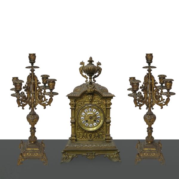 Orologio da tavolo e due candelieri in bronzo dorato a cinque luci