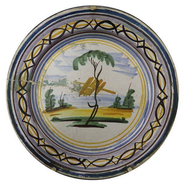Caltagirone majolica plate. In the center, river landscape with trees