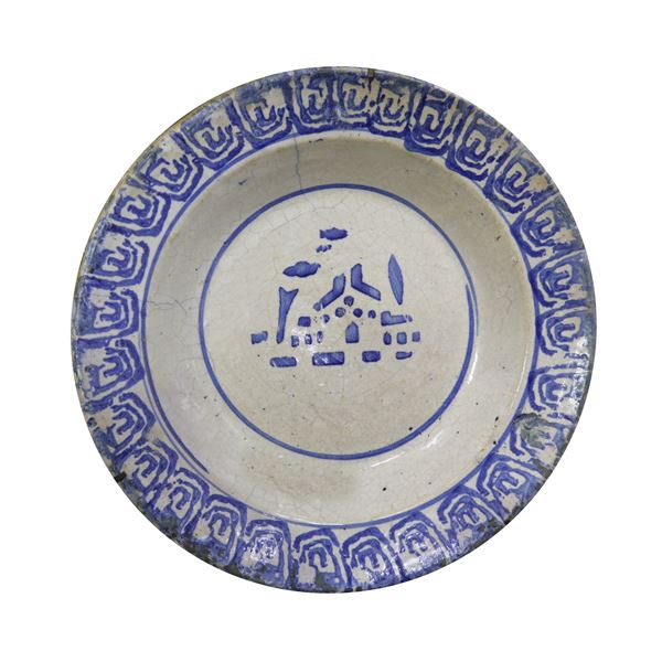 Majolica plate painted with blue flowers on a white background and bowl with a light blue house and clouds in the center on a white background