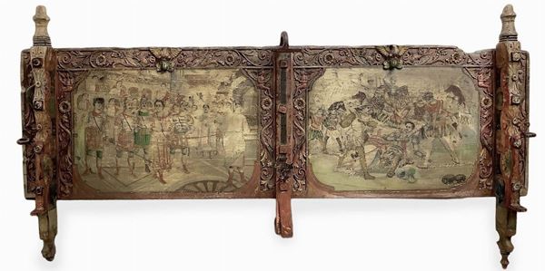 Sicilian cart "sponda" painted in two sections, with two polychrome squares, Sicily nineteenth / twentieth century beginnings. Depicting Berenice dragged in chains from Agrippe .Intagli eagles, angels and dragons, paintings of butterflies and flowers, iron at the forge of heads with helmets and flowers 126x63 cm.
