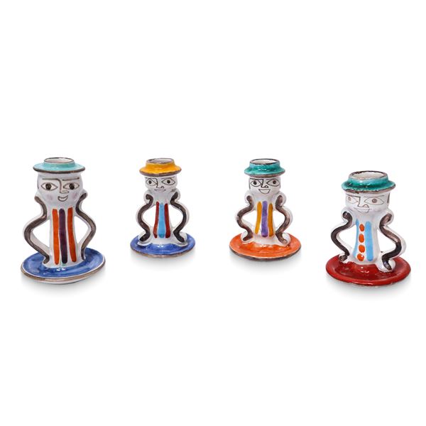 Four single-hole candle holders in polychrome porcelain, hand-painted with faces.