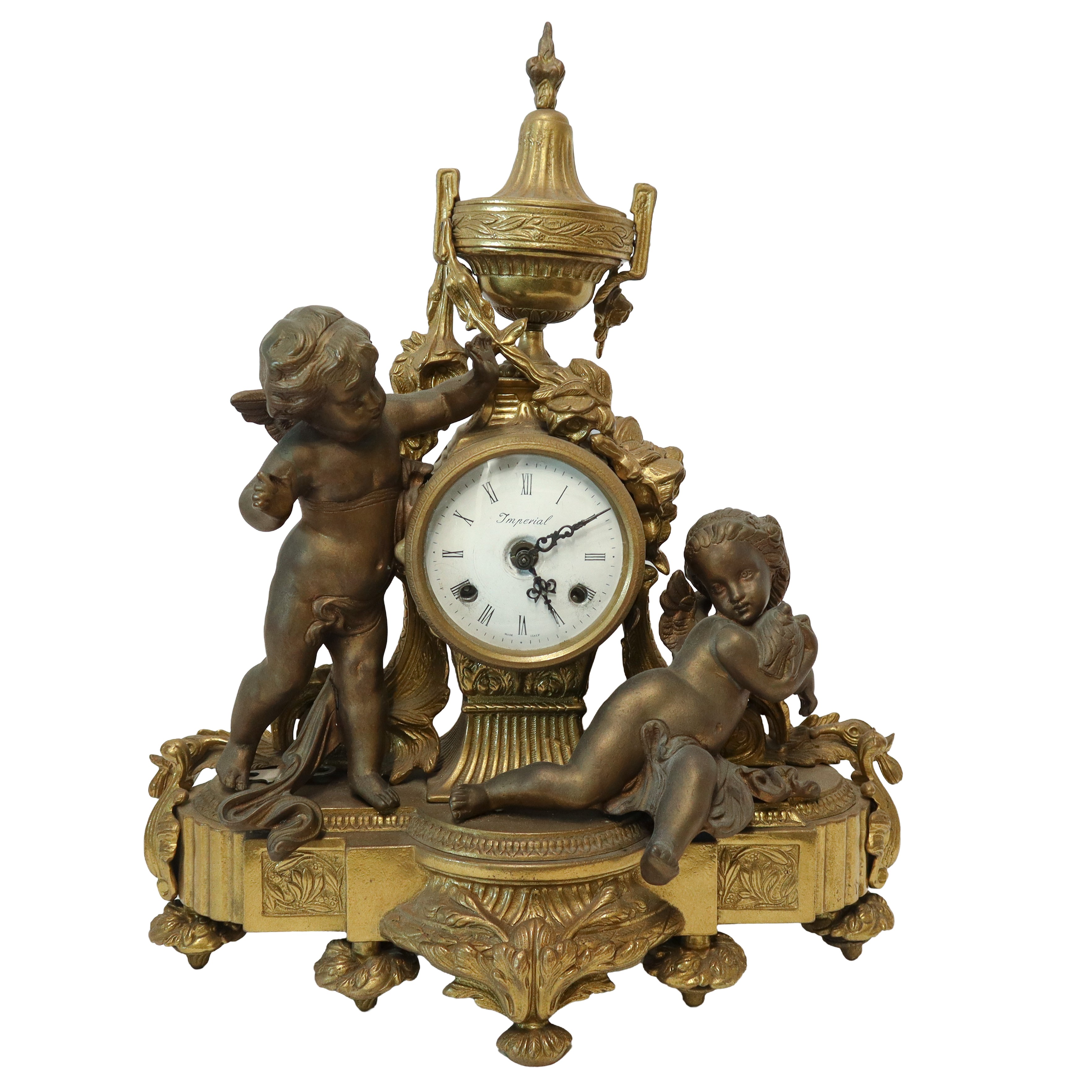 Trittico composto da orologio da tavolo in bronzo patinato oro con putti ai lati, quadrante in po...
