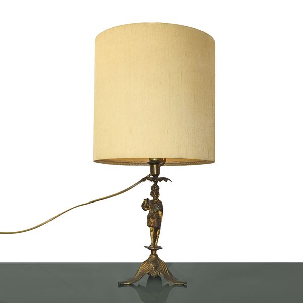 Lamp with golden brass base depicting a character with fabric lampshade