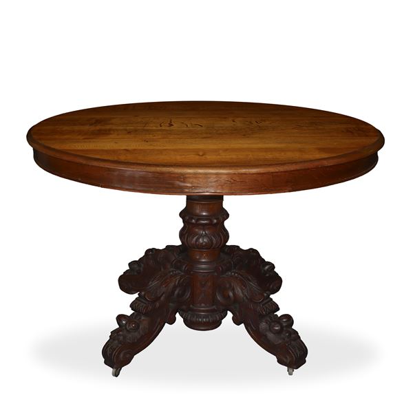 Extendable oval table in walnut with four-spoke foot in sculpted and carved wood