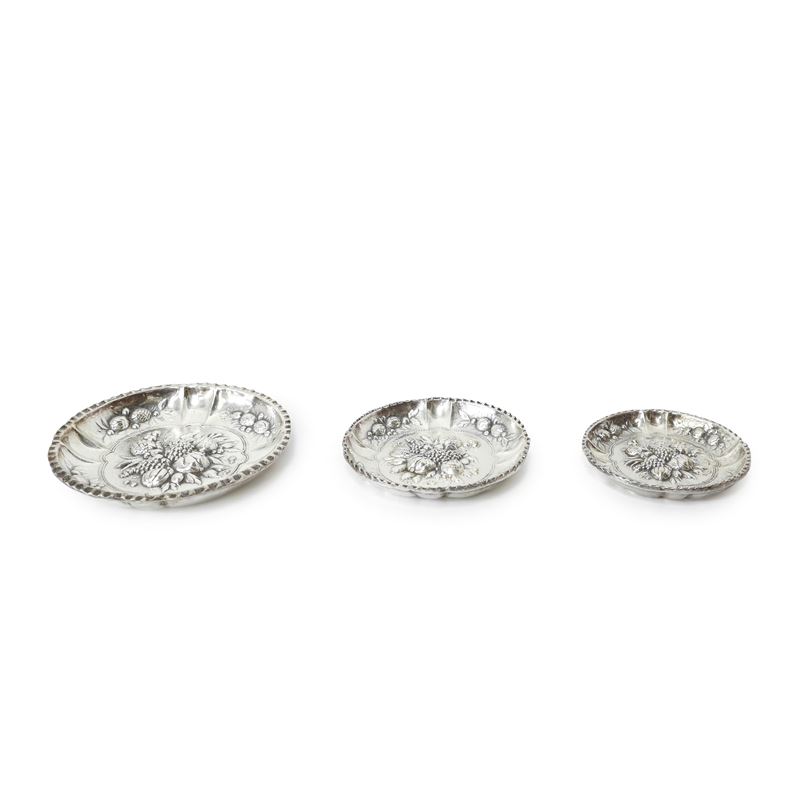 Tris di piattini in silver con decorazioni di frutti a sbalzo in argento, diametri 9,6 - 11,3 - 1...