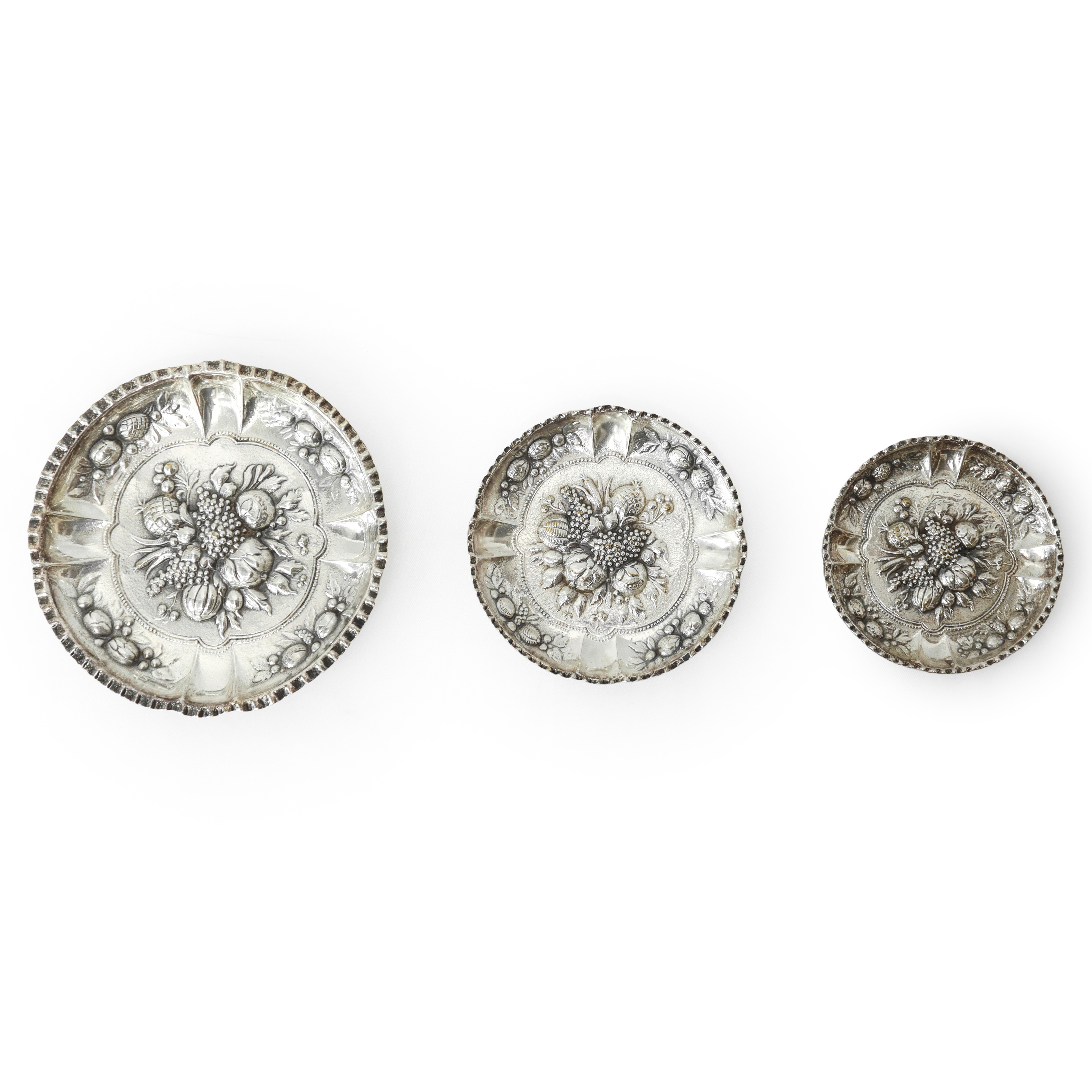 Tris di piattini in silver con decorazioni di frutti a sbalzo in argento, diametri 9,6 - 11,3 - 1...
