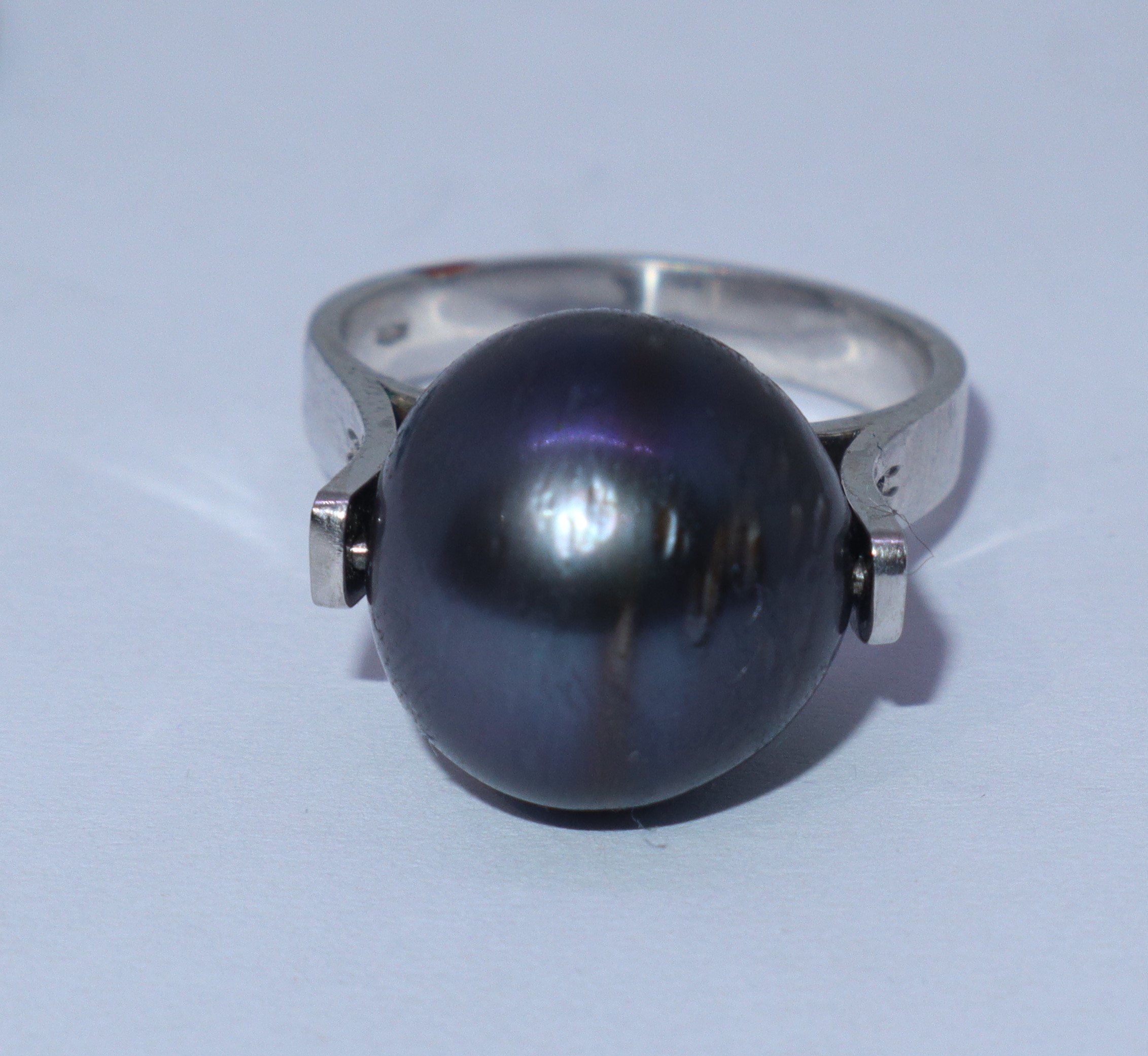 Anello in oro bianco con perla grigia e file di brillantini ai lati della perla