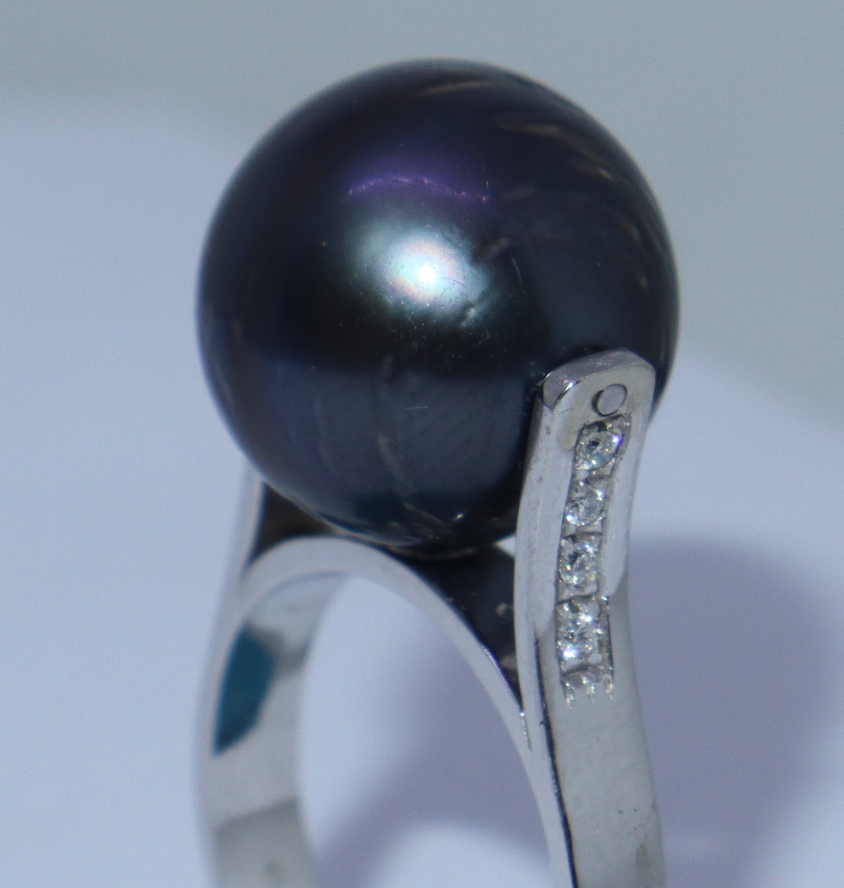 Anello in oro bianco con perla grigia e file di brillantini ai lati della perla