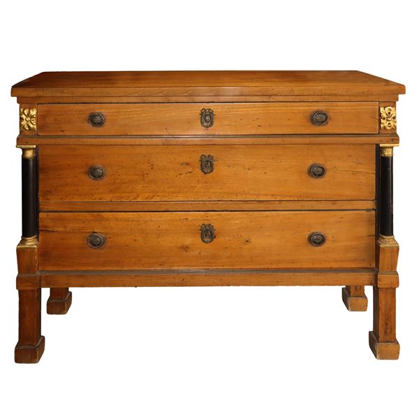 Chest of drawers in light walnut wood with three drawers with black columns on the empire sides and golden brass studs on the drawers