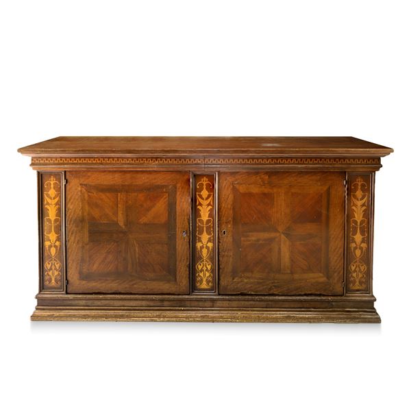 Walnut wood sideboard with two drawers under the top, walnut top with a bird&#39;s beak, two doors at the base with light wood inlays on the sides of the base, graduated frame