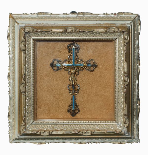 Crucifix in silver and gold metal with enamels, in a display case.