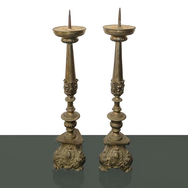 Coppia di candelieri in bronzo con base sbalzata triangolare e decori