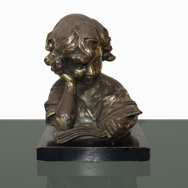 Girl reading a book in gold patinated terracotta on a wooden base