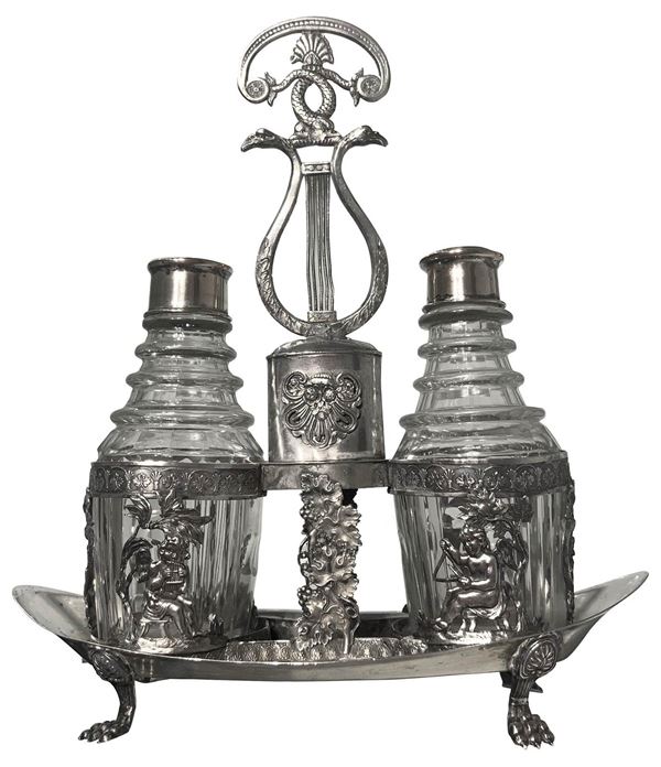 Saliera in argento, Berlino, inizi XIX Secolo. Base ovale poggiante su piedi a zampa felina. Porta ampolle sostenuti da cherubini. H cm 27. Gr 380