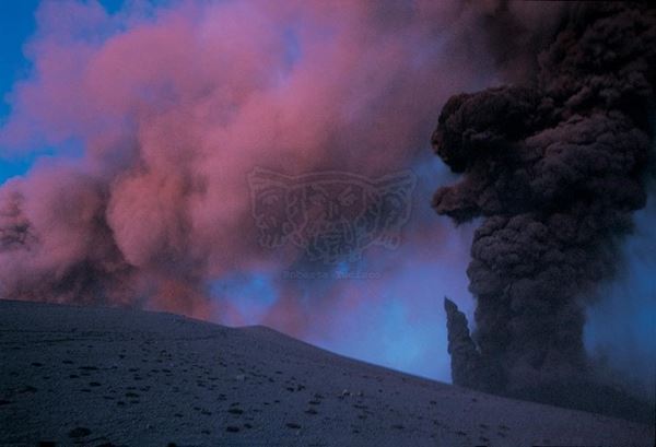 Collezione EM, titolo "Pinksmoke", anno 2002. Etna: eruzione 2002, esplosione con sabbia vulcanica in primo piano, sullo sfondo fumo dal cratere colorato dalla luce del tramonto, diapositiva  1 / 8 , 30x45, CIBACHROME stampa diretta da diapositiva , 40x55 forex 10mm, perfilo bianco, cartoncino, bordi rivestimento sabbia vulcanica 