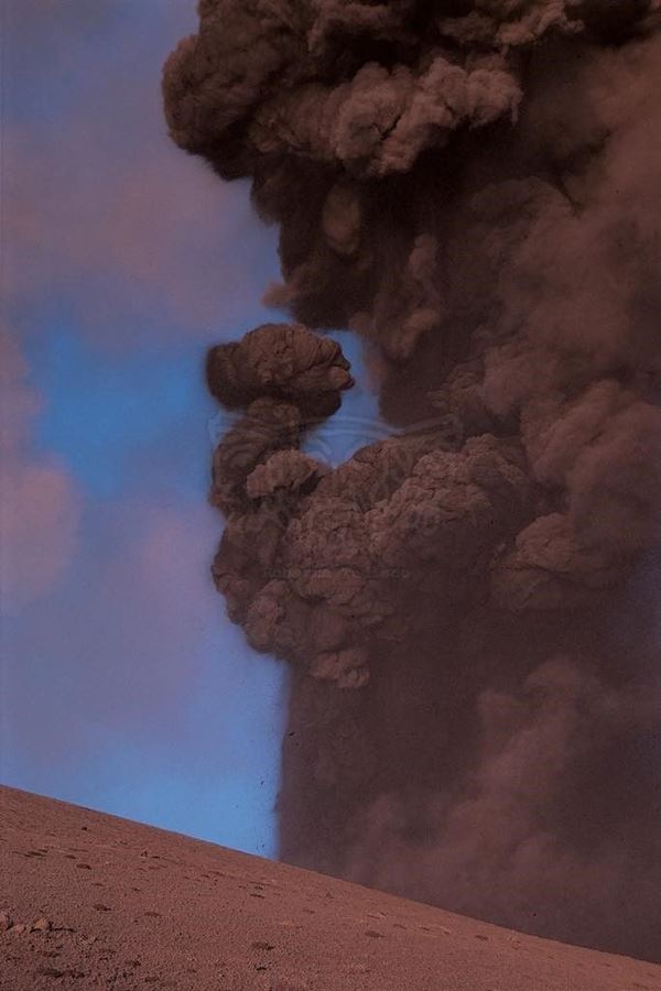 Collezione EM, titolo "FHB", anno 2002. Etna: eruzione 2002, esplosione con sabbia vulcanica (dettaglio) sullo sfondo fumo dal cratere colorato dalla luce del tramonto, diapositiva  1 / 8 , 30x45, CIBACHROME stampa diretta da diapositiva , 40x55 forex 10mm, perfilo bianco, cartoncino, bordi rivestimento sabbia vulcanica 