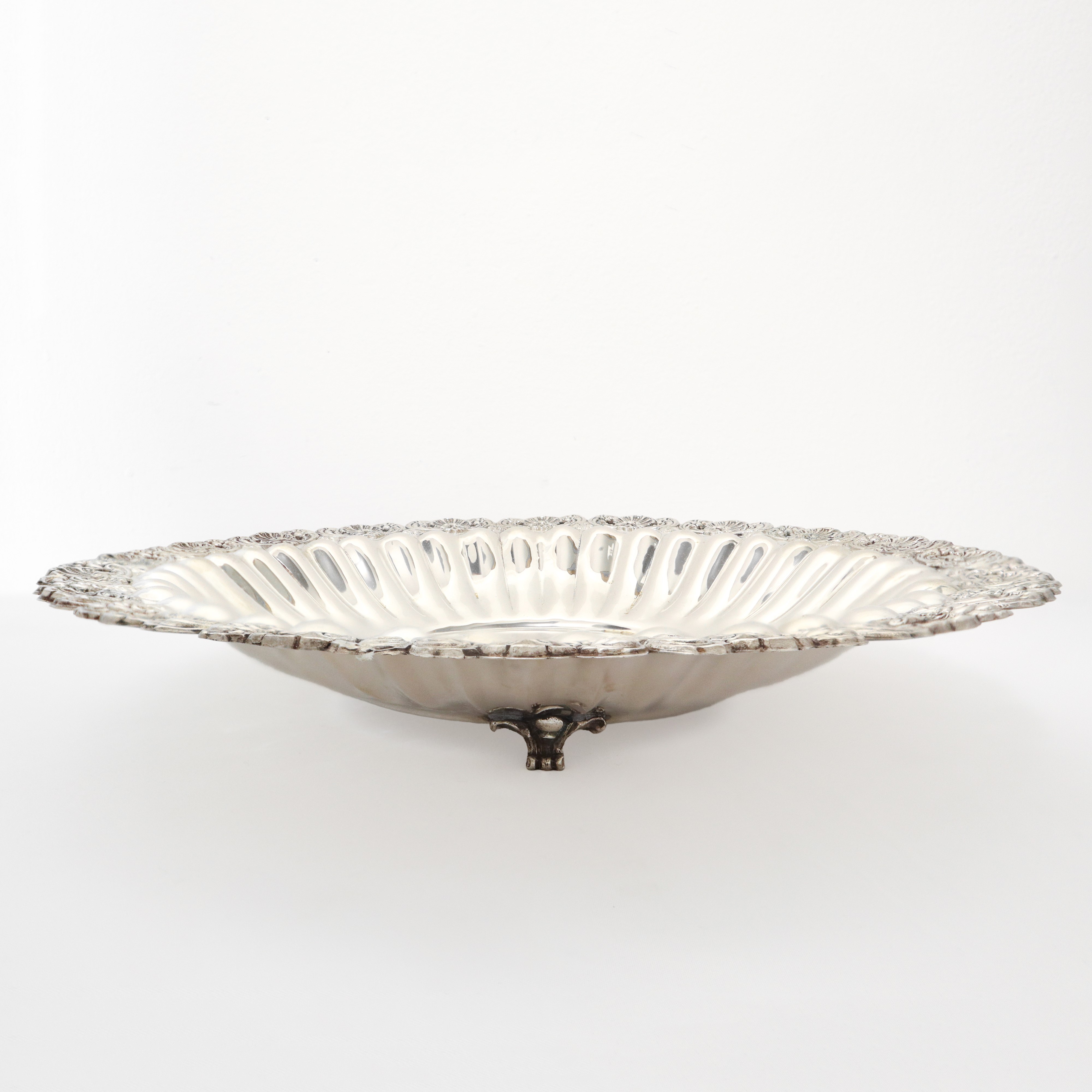 Centrotavola circolare in argento 800 con piedi di sostegno e bordo sbalzato e smerlato a conchig...
