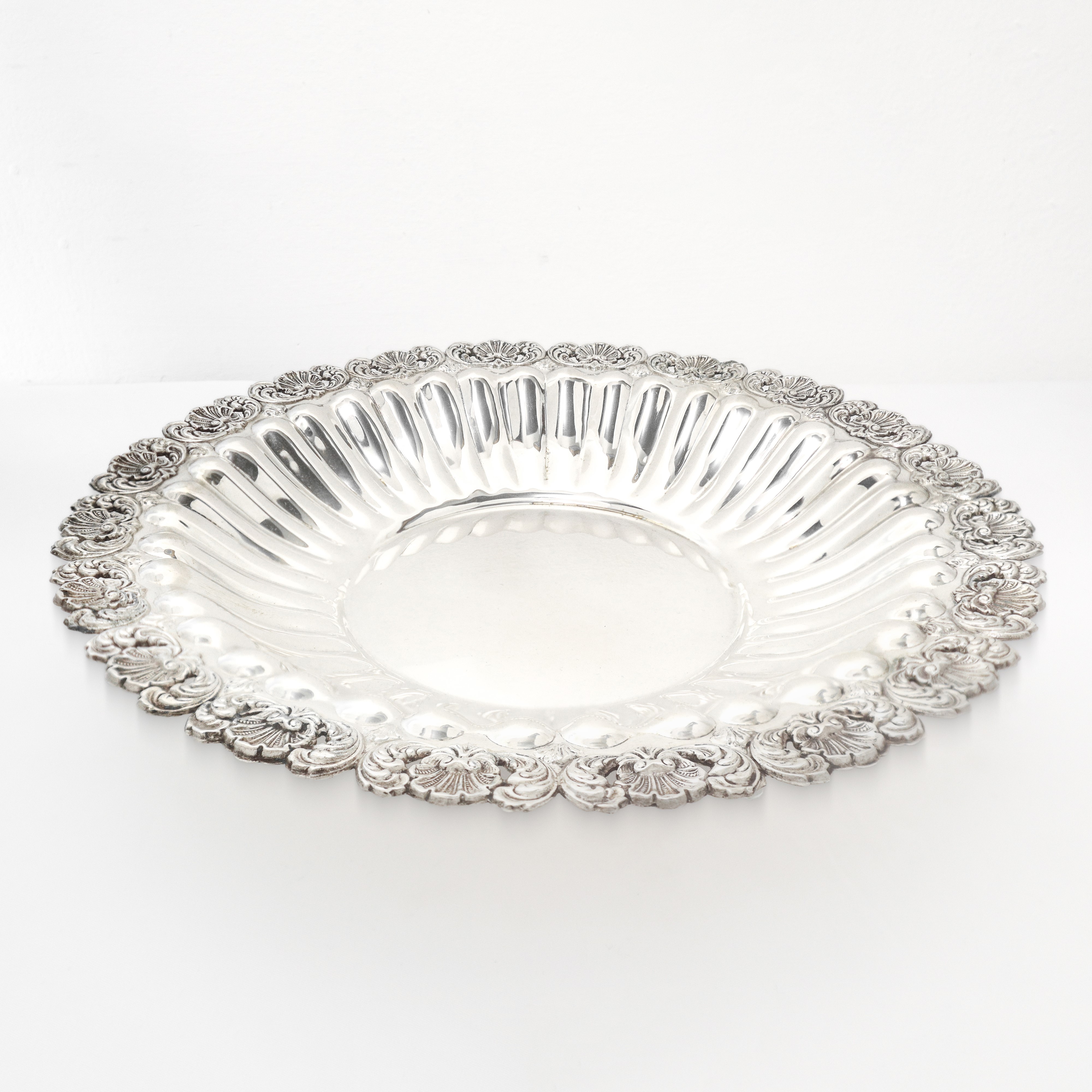 Centrotavola circolare in argento 800 con piedi di sostegno e bordo sbalzato e smerlato a conchig...