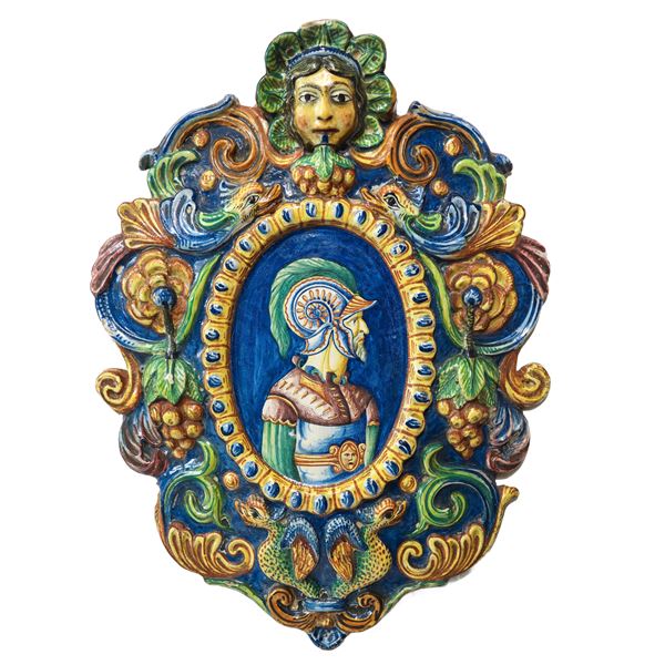 Medaglione in ceramica di Caltagirone policroma e decorata in rilievo con frutti e motivi zoomorfi con figura di paladino al centro