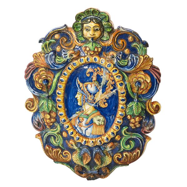 Medaglione in ceramica di Caltagirone policroma e decorata in rilievo con frutti e motivi zoomorfi con figura di paladino al centro