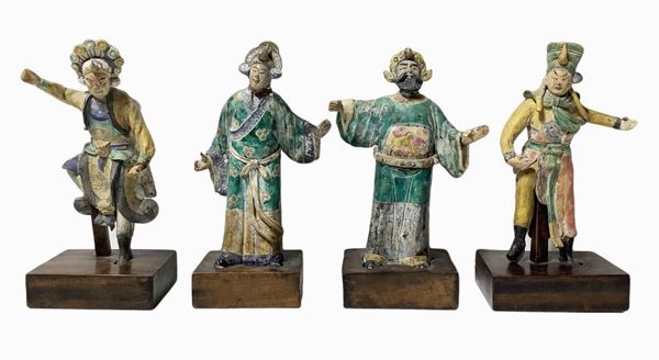 Gruppo di quattro antiche statuette raffiguranti personaggi cinesi in terracotta. Base in legno cm 4. H totale cm 30. Sul retro tracce di incollature al muro. Rotture e mancanze