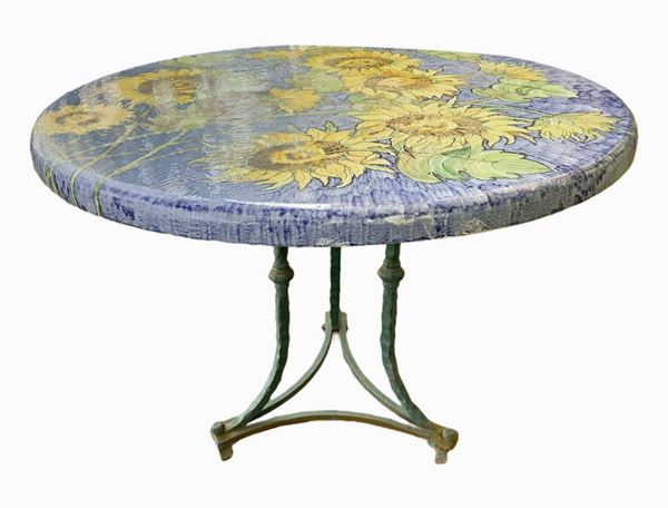 Round table in lava stone decorated with polychrome ceramic with sunflowers on the floor. 20th century, h 60 cm, 80 cm diameter carrying iron ...