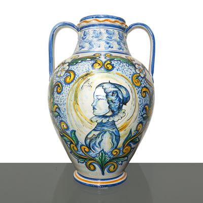 Vaso biansato in maiolica con decorazioni floreali e volto femminile