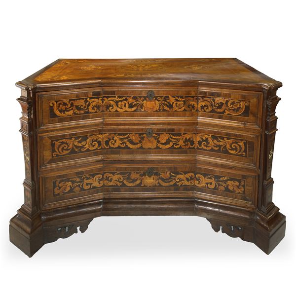 Cassettone veneto in legno di noce intarsiato con legni di acero, palissandro ed ebano piano di forma sagomata ed angoli scantonati, tre cassetti interamente intarsiati a motivi di ghirlande lati intarsiati a motivi fogliari con grandi uccelli entro tarsie rettangolari, piano interamente intarsiato in legni chiari